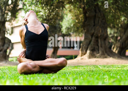 Bella donna a praticare yoga nel parco.La bloccato Lotus pongono Baddha Padmasana Foto Stock