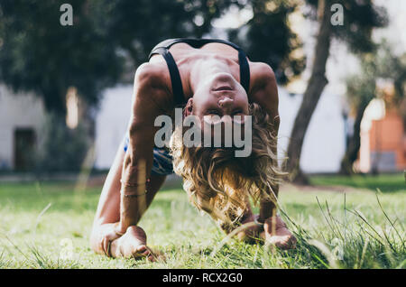 Lo Yoga - all'aperto giovane bella donna slanciata istruttore yoga facendo camel pongono Ustrasana asana esercizio all'esterno. Vintage effetto retrò filtrata hipster style immagine. Foto Stock