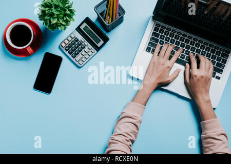 Donna mano utilizzando computer sulla scrivania blu.vista superiore con copia spazio. Foto Stock