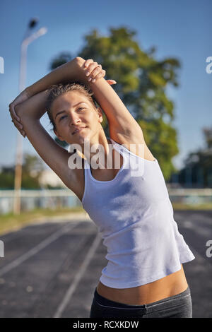 Giovani runner montare donna allungando prima di esercizi all'esterno. Femmina atletico strech dopo allenamento al di fuori. Lo sport e il concetto di popolo. Foto Stock