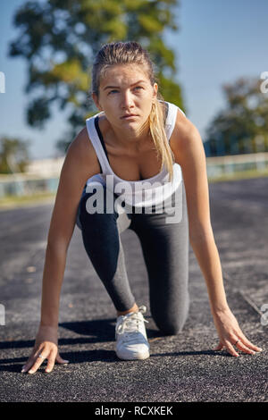 Una giovane donna runner pronti per una corsa su pista Foto Stock