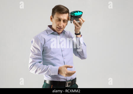 Giovane uomo appoggiata contro la testa del raffreddatore dal computer isolati su uno sfondo luminoso Foto Stock