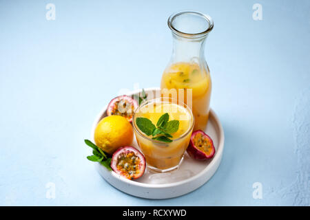 La limonata con il frutto della passione, menta in un bicchiere, frutto della passione su uno sfondo blu Foto Stock
