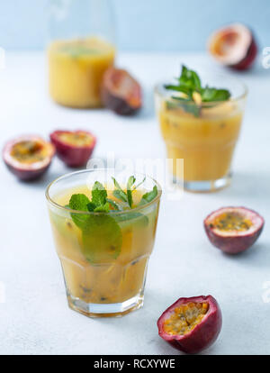 Succo tropicale con frutto della passione, menta in un bicchiere, frutto della passione su uno sfondo blu Foto Stock
