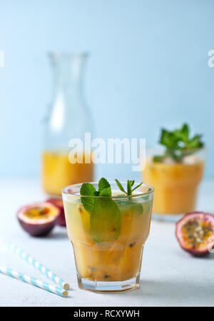 Succo tropicale con frutto della passione, menta in un bicchiere, frutto della passione su uno sfondo blu Foto Stock