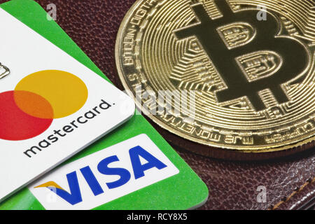 Carta di credito Visa, Mastercard e golden bitcoin con il portafoglio in pelle sullo sfondo. Foto Stock