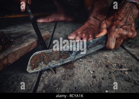 Muara Siberut, isole mentawai / Indonesia - 15 AGO 2017: Tribal uomo la sua affilatura freccia per la caccia a sua giungla home Foto Stock