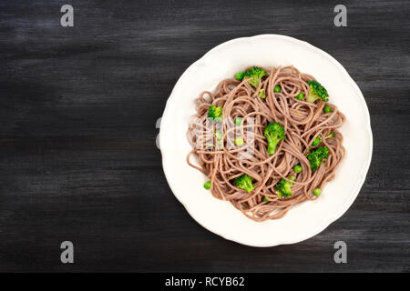 Una piastra di cottura soba, Tagliatelle di grano saraceno con sani di verdura verde, ripresa dall'alto su sfondo scuro con un posto per il testo Foto Stock