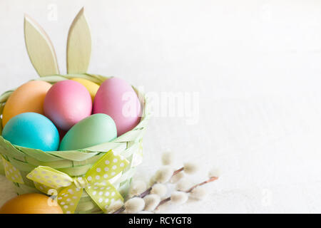 Pasqua colorfgul semplice le uova nel paniere e coniglietto bianco su sfondo di legno Foto Stock