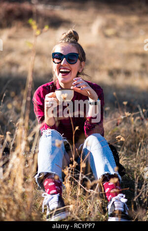 Donna con una tazza di caffè mentre il picnic all'aperto Foto Stock