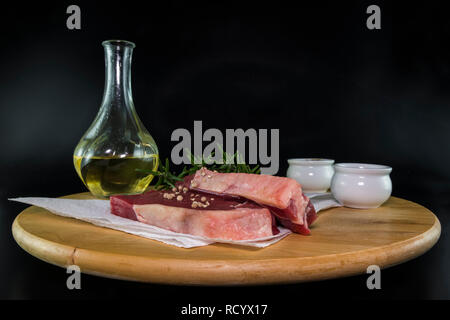 Due entrecote bistecca su un tagliere di legno con olio di oliva Rosmarino sale e pepe pronti per la cottura Foto Stock