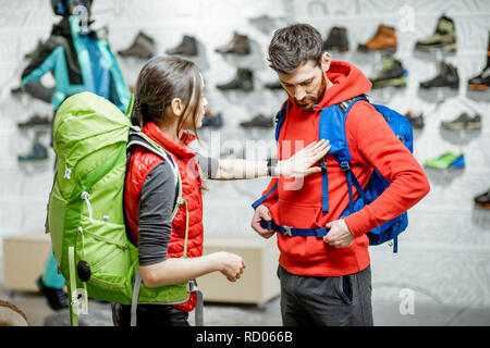 Coppia giovane di viaggiatori cercando nuovi zaini nel negozio di abbigliamento sportivo e attrezzature Foto Stock