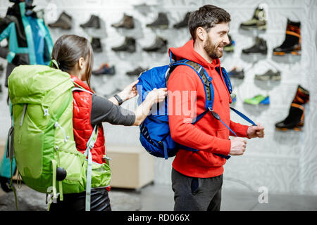 Coppia giovane di viaggiatori cercando nuovi zaini nel negozio di abbigliamento sportivo e attrezzature Foto Stock