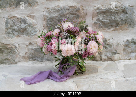 Wedding bouquet di fiori diversi su un muro di pietra sullo sfondo Foto Stock