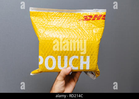 Parigi, Francia - Mar 24, 2018: punto di vista maschile e la mano con DHL Express pacco giallo custodia in plastica Foto Stock