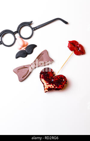 Parte superiore piatta o vista laici di Photo Booth puntelli un baffi, bicchieri, cuore rosso forma e un filtro bow tie isolato su bianco le feste di compleanno, matrimoni, Valentino d Foto Stock