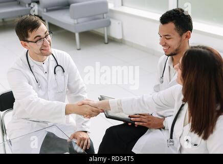 Stretta di mano del colleghi medici presso la scrivania in ufficio in ospedale Foto Stock