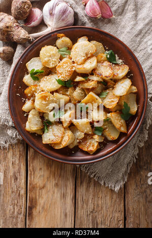 Gerusalemme i carciofi arrosto con aglio, il formaggio e il prezzemolo closeup su una piastra sul tavolo. Verticale in alto vista da sopra Foto Stock