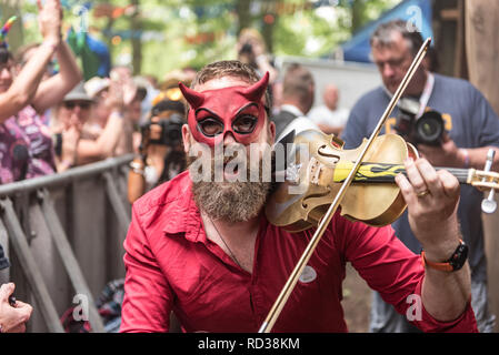 Uomo vestito come il diavolo a suonare il violino a un festival di musica Foto Stock