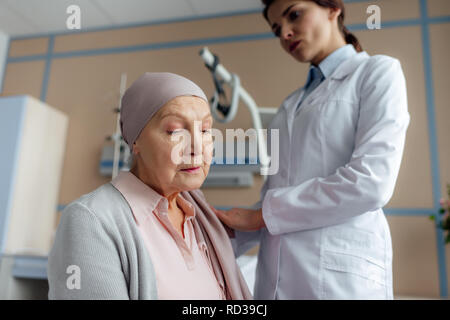 Medico donna consolante triste senior donna nel fazzoletto con il cancro in ospedale Foto Stock