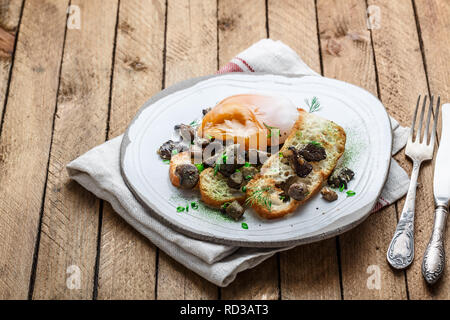 Uovo cremoso con pane e funghi su una piastra Foto Stock
