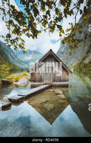 Visione idilliaca della tradizionale antica imbarcazione in legno house presso il pittoresco lago Obersee su una bella giornata di sole con cielo blu e nuvole in estate, Baviera, Germania Foto Stock