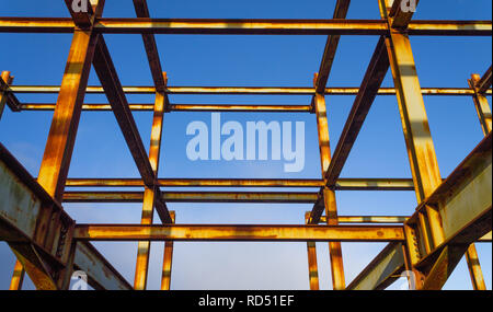 Ruggine di acciaio laminato travetto scheletro di un edificio delineato contro un cielo blu Foto Stock