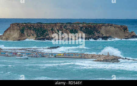 Mare mosso la pastella al porto di Agios Georgios, a Cipro con la piccola isola di Yeronisos dietro. Foto Stock