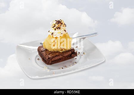 Celeste con dessert gelato, panna montata, spruzza e brownie al cioccolato sulla piastra bianca, pallido Sfondo nuvola Foto Stock