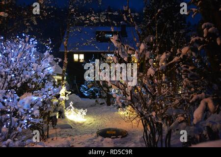 Piccola casa coperte di neve e chtistmas luci nel pittoresco Bad Goisern, Hallstatt. Austria. Vista del tramonto. Foto Stock