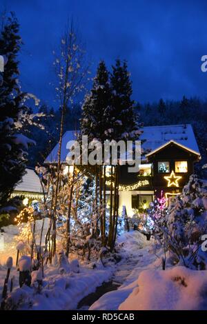 Piccola casa coperte di neve e chtistmas luci nel pittoresco Bad Goisern, Hallstatt. Austria. Vista del tramonto. Foto Stock