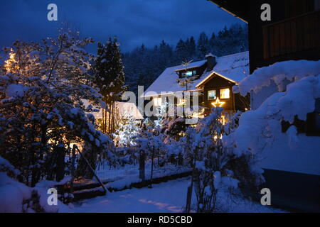 Piccola casa coperte di neve e chtistmas luci nel pittoresco Bad Goisern, Hallstatt. Austria. Vista del tramonto. Foto Stock