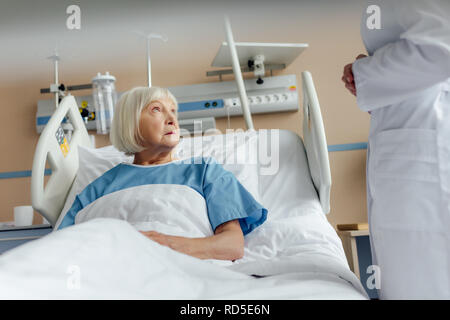 Consulenza medico sconvolto senior donna giaceva nel letto di ospedale Foto Stock