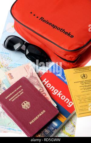 Kit di primo soccorso, passaporto, carta di vaccinazione, occhiali da sole e guida di viaggio Foto Stock