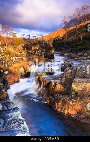 Bordo di rocce in alto sopra il fiume Etive, un posto di primo piano per catturare la cascata & montagna illuminata dal bagliore del caldo tramonto Foto Stock