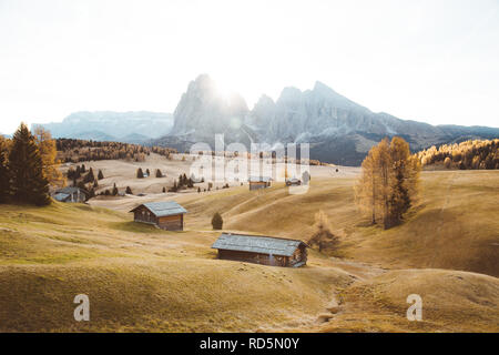 Bellissima vista del legno tradizionale chalet di montagna su SCENIC Alpe di Siusi con il famoso Sassolungo picchi di montagna in background in golden mattina Foto Stock
