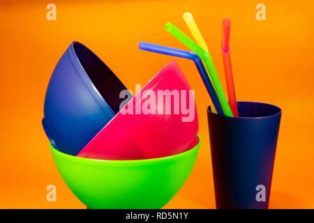 In plastica colorata Ciotole Coppe e cannucce colorate su sfondo arancione, un mondo libero del concetto di plastica Foto Stock