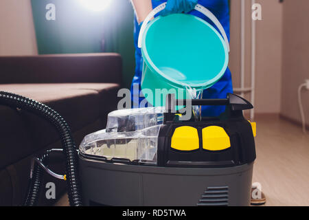 Attrezzature professionali per il lavaggio a secco. chimica, estrattore, versa acqua dentro l uomo dai colori uniformi e indumenti da lavoro. Foto Stock