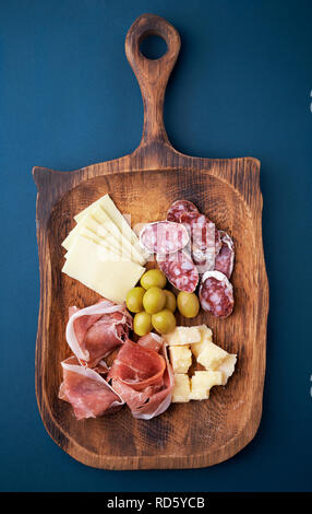 Gli antipasti. carni fredde e formaggi su una lastra di legno. vista superiore Foto Stock