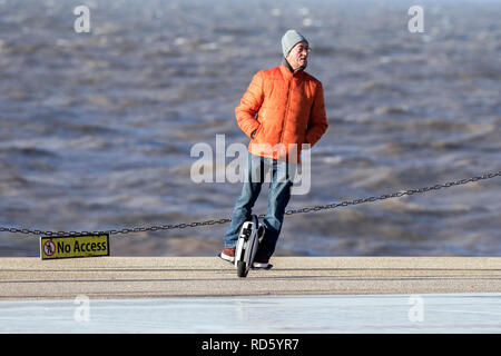 Un uomo che cavalca il suo bilanciamento automatico monociclo gyro scooter lungo la Promenade di Blackpool, Lancashire, Regno Unito Foto Stock