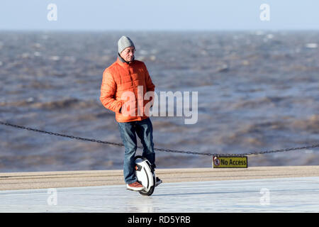 Un uomo che cavalca il suo bilanciamento automatico monociclo gyro scooter lungo la Promenade di Blackpool, Lancashire, Regno Unito Foto Stock