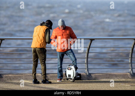 Un uomo che cavalca il suo bilanciamento automatico monociclo gyro scooter lungo la Promenade di Blackpool, Lancashire, Regno Unito Foto Stock