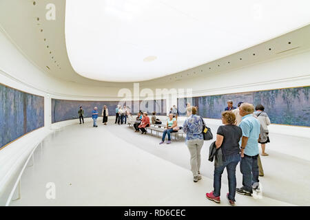 Le persone che guardano le gigli d'acqua di Claude Monet sono allestite in pannelli curvi in una stanza di forma ovale all'Orangerie o al Musee de l'Orangerie, Parigi, Francia Foto Stock