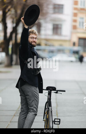 Bello ed elegante hipster uomo Bicicletta Equitazione e salutando. Foto Stock