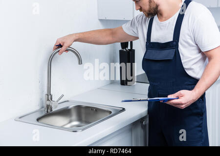 Vista parziale di aggiustatore nel lavoro globale negli appunti di trattenimento e di controllo del lavello in cucina Foto Stock