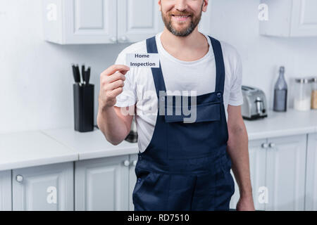 Ritagliato shot di maschio tuttofare holding toolbox e mostra la scheda con scritte di ispezione iniziale Foto Stock