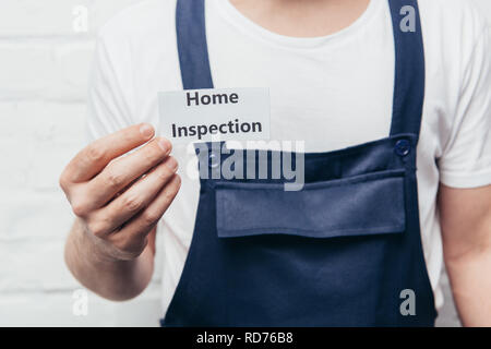 Immagine ritagliata maschile di artigiano che mostra la scheda con scritte di ispezione iniziale Foto Stock