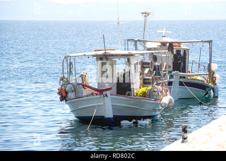 Di piccole dimensioni e di colore bianco sovraccaricato la pesca in barca ancorata accanto al dock. Foto Stock