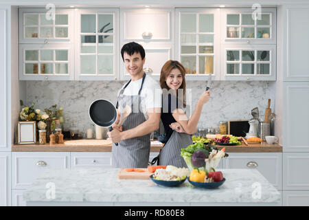 Coppia giovane preparare il cibo insieme al contatore in cucina. Felice amore giovane concetto. Foto Stock