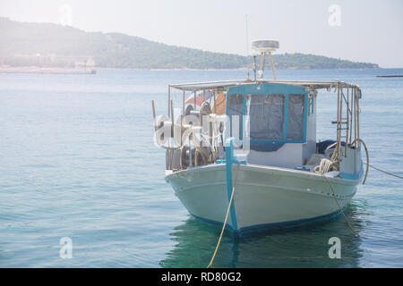 Di piccole dimensioni e di colore bianco sovraccaricato la pesca in barca ancorata accanto al dock. Foto Stock